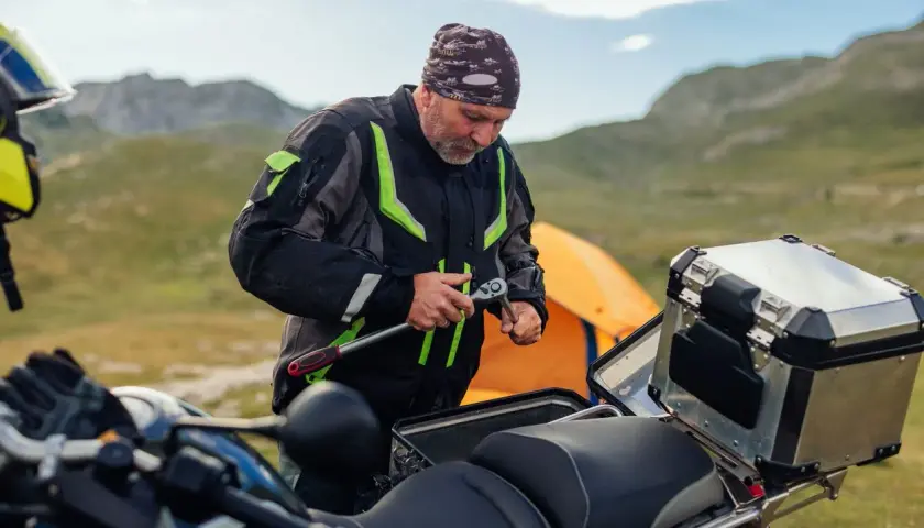 Motociclista repara su moto en la montaña, quizás para evitar que se ahoga la moto.