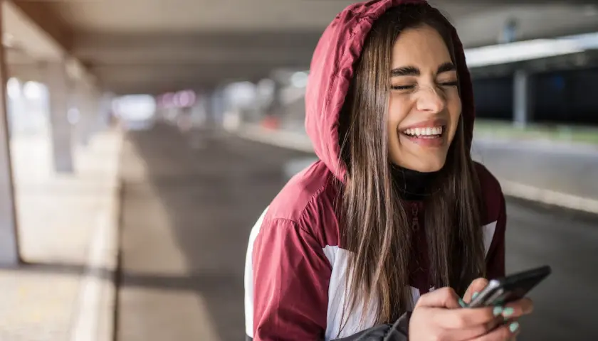 Ragazza ride a crepapelle guardando il telefono, un momento che fa capire che significa lmao.