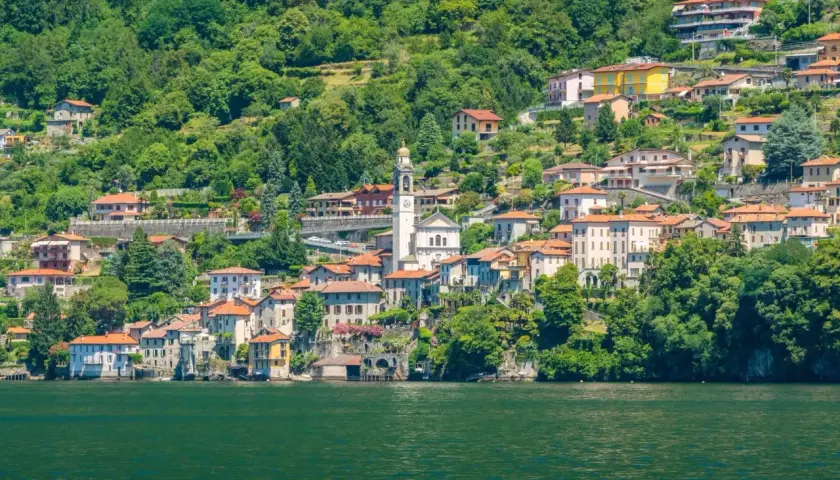 Ein malerisches Dorf am Nesso Comer See, mit traditionellen Häusern, die sich an den grünen Hang schmiegen.