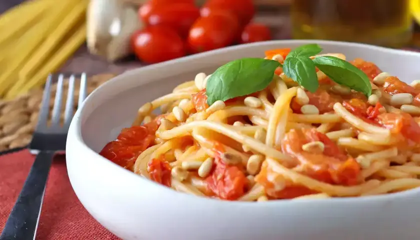 Spaghetti con pomodorini, pinoli e basilico, uno dei tanti sughi per pasta che invitano a gustare la semplicità.