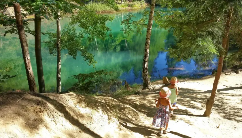 Dwie dziewczynki w słomkowych kapeluszach idą ścieżką nad turkusowe jezioro. Idealne miejsce, gdzie w góry z dziećmi.