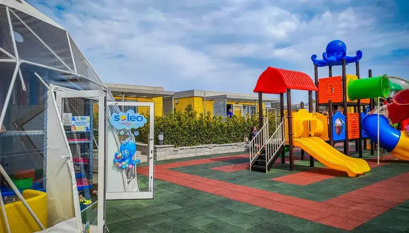 Kolorowy plac zabaw z ośmiornicą i zjeżdżalniami, idealne rewa atrakcje dla dzieci. Obok namiot z atrakcjami dla najmłodszych.