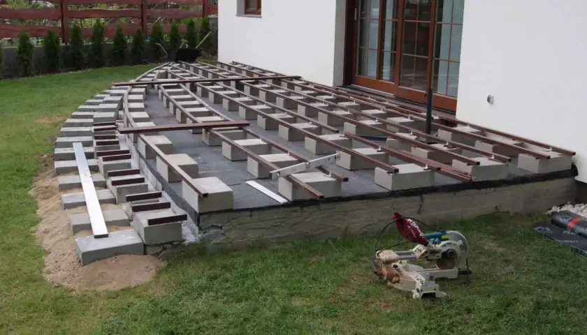 Budowa tarasu kompozytowego: widać betonowe bloczki i legary, które wyznaczają rozstaw co ile legary pod taras kompozytowy.