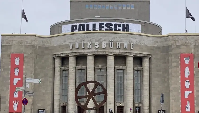 Volksbühne Berlin mit Banner "POLLENSCH". Annegret Hahn könnte hier eine Aufführung besuchen. Rote Banner mit Gebärdensprache.