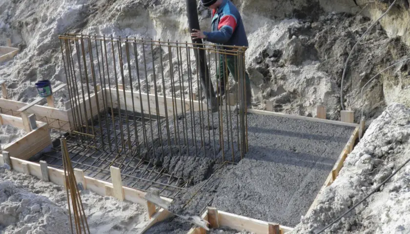 Wylany beton w szalunku, pracownik wylewa masę, mimo że czuć już przymrozek.