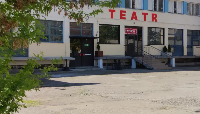 Teatr Druga Strefa. Budynek z czerwonym napisem "TEATR" na fasadzie, wejście z wielojęzycznym napisem "WEJŚCIE".