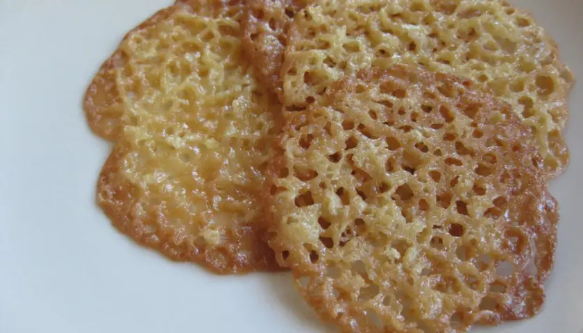 Tre gyllene, krispiga havreflarn ligger på en vit tallrik. Perfekta för ett enkelt recept på havreflarn.