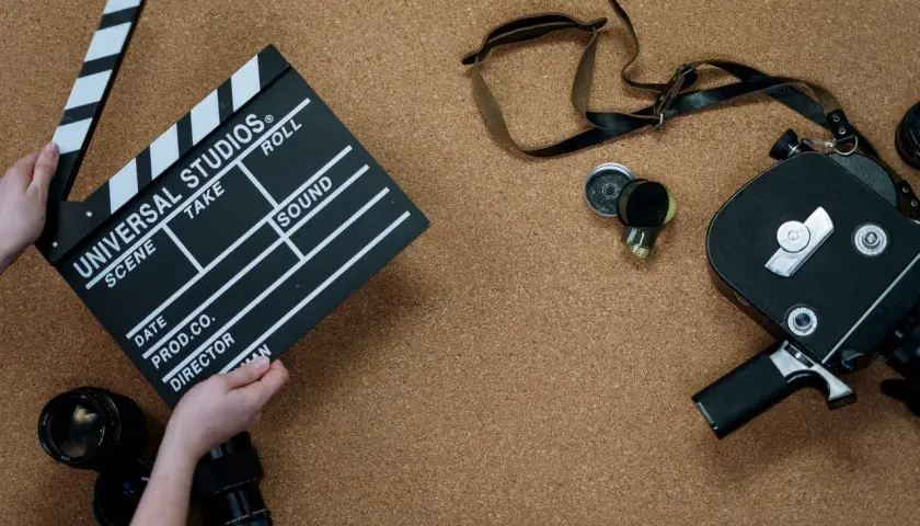 Kamera filmowa, klaps z napisem "Universal Studios" i obiektywy. To wszystko, co potrzebne do stworzenia opisu filmu po angielsku.