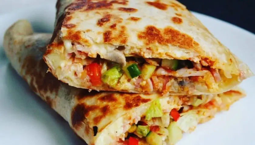 Złocista tortilla z jajkiem, serem i szynką, wypełniona warzywami, usmażona na patelni. Pyszne danie na szybki posiłek.