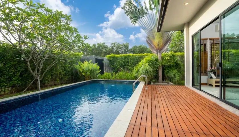 Piscine extérieure avec terrasse en bois, entourée de verdure luxuriante. Un espace de détente qui respecte l'esprit de l'article R.111-19 du code de l'urbanisme.