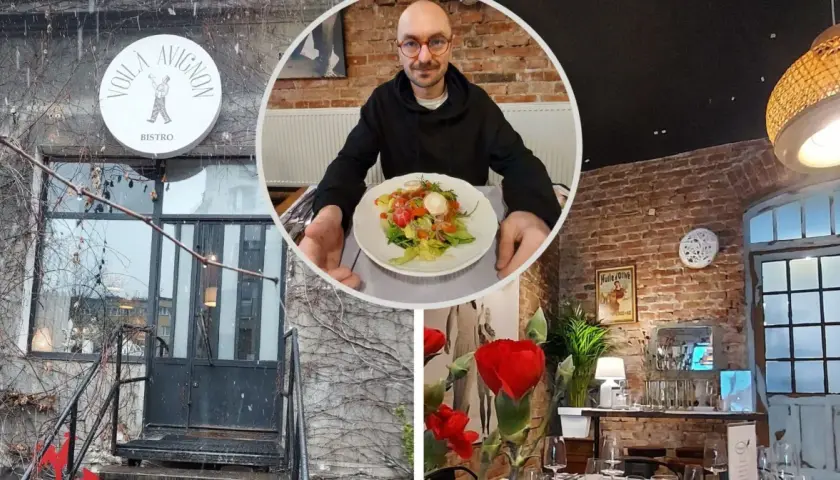 Voila, co znaczy to bistro! Mężczyzna z okularami prezentuje sałatkę w przytulnym wnętrzu z ceglanymi ścianami i stylowymi lampami.