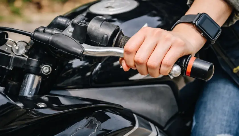 Mano sujetando el manillar de una moto negra, lista para arrancar. Aprender a no picar embrague es clave para una conducción suave.