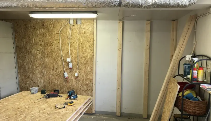Här ligger skivor av OSB redo att måla. Verktyg och byggmaterial finns på plats för projektet.