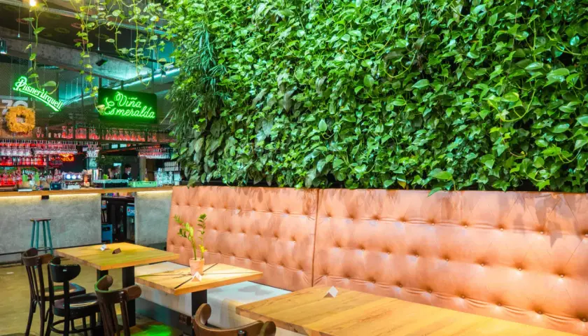 Wnętrze restauracji z zieloną ścianą, neonem "Viña Esmeralda" i wygodnymi lożami. Idealne miejsce na liście top 10 restauracji w Krakowie.