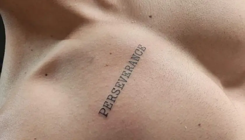 Tatuaż na klatce piersiowej z napisem "PERSEVERANCE" symbolizujący siłę i wytrwałość w dążeniu do celu.