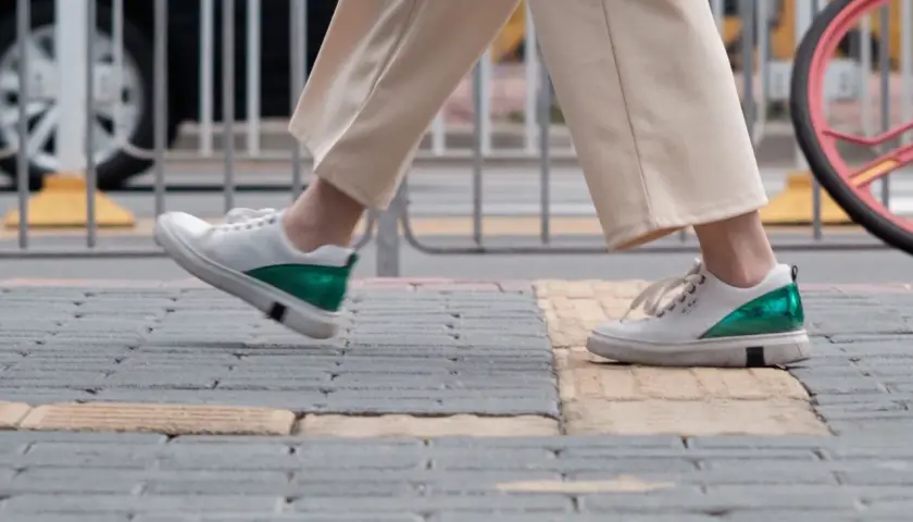 Białe sneakersy z zielonym akcentem na pięcie, idealne na spacer. Zastanawiasz się, jaki rozmiar buta francuski a polski wybrać?