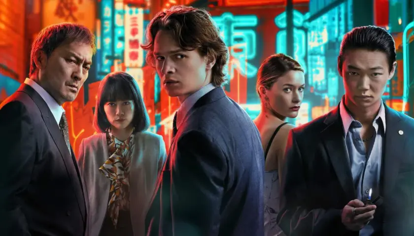 Fem personer poserar framför neonupplysta skyltar i Tokyo. En ung man i kostym blickar intensivt mot kameran, en scen som fångar essensen av "Tokyo Vice".