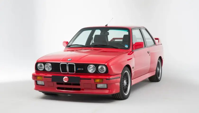 Klasyczne czerwone bmw e30 coupe z czarnymi felgami i emblematem M3. Ikona motoryzacji.