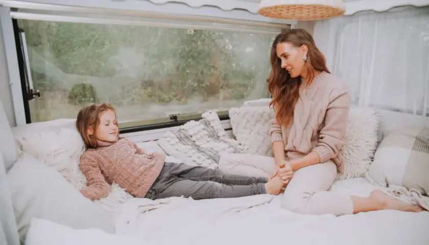 Mama i córka odpoczywają w przytulnym kamperze. Czy w kamperze można spać podczas jazdy? To pytanie zadaje sobie wielu podróżników.