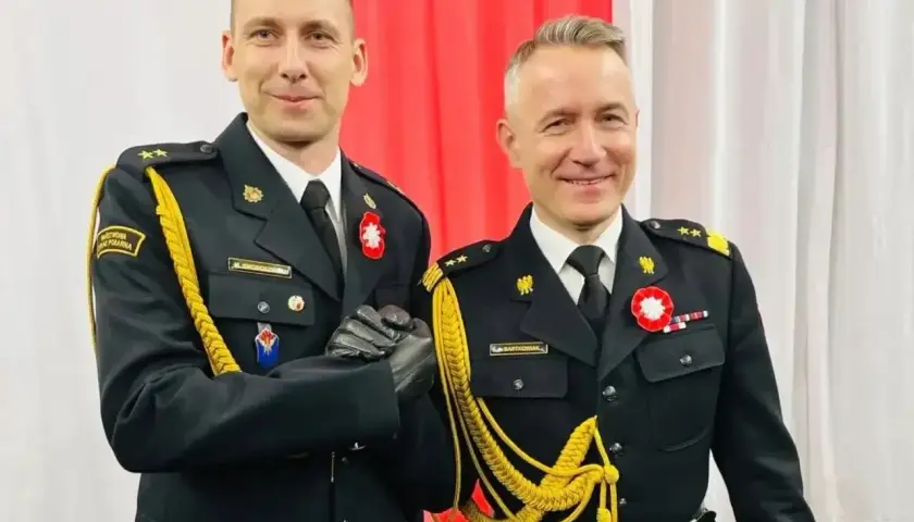 Dwóch mężczyzn w galowych mundurach, z bogatym **uposażeniem**, ściska sobie dłonie.