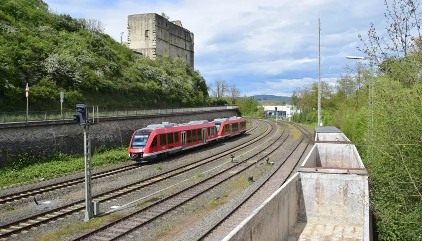 Roter Zug fährt auf Gleisen an einer Burgruine vorbei. br 640.