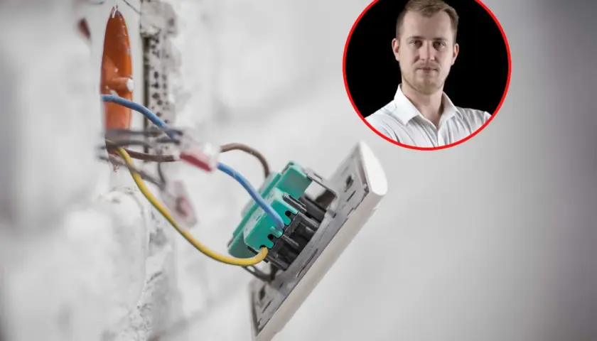 Prąd budowlany w ścianie, instalacja elektryczna w trakcie prac. W tle mężczyzna w białej koszuli.