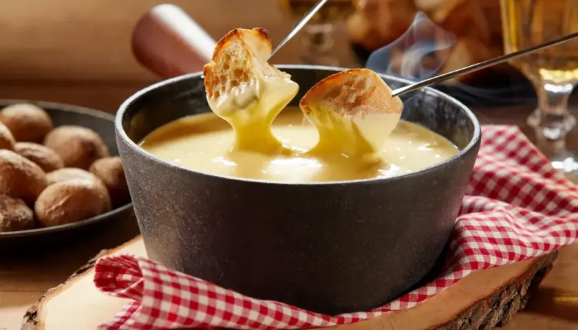 Un délicieux moment de partage autour d'une fondue savoyarde crémeuse, avec du pain croustillant trempé dans le fromage fondu.
