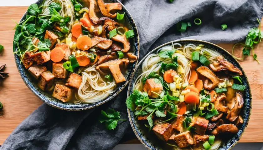 Två skålar med nudlar, svamp, morötter och krispiga tofu-bitar. Ett perfekt tofu recept för en värmande måltid.
