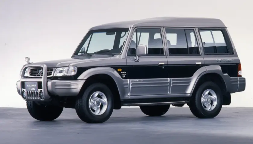 Srebrny Hyundai Galloper V6 LPG, terenowy SUV z lat 90. z czarnymi pasami na drzwiach.