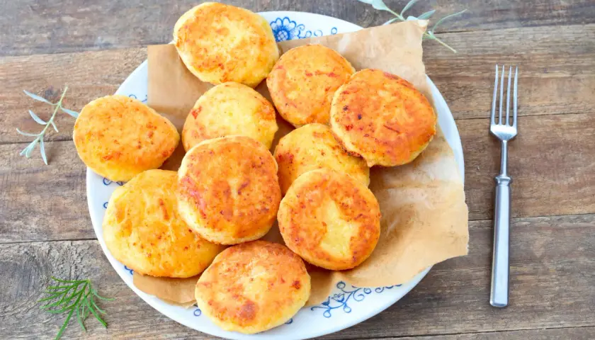 Talerz pełen złotych placków kukurydzianych (arepas) z widelcem obok.