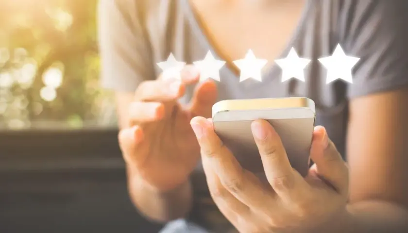 Une personne utilise son smartphone pour laisser un avis 5 étoiles, un élément clé du marketing digitale.