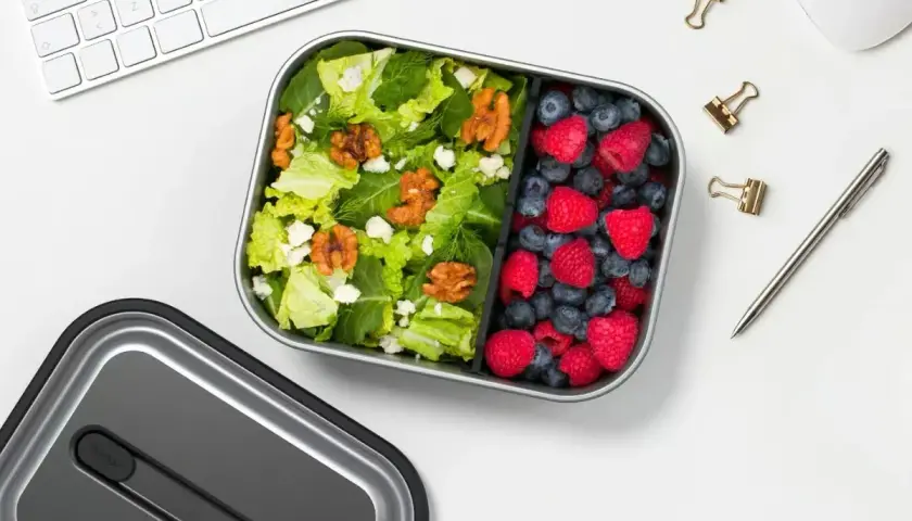 A healthy lunch bento box with a fresh salad and berries, perfect for a desk lunch, not a curry bento box.