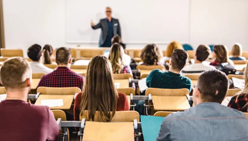 Dozent spricht vor Studenten im Hörsaal. Viele junge Leute, die vollzeit arbeiten und studieren, sind aufmerksam.