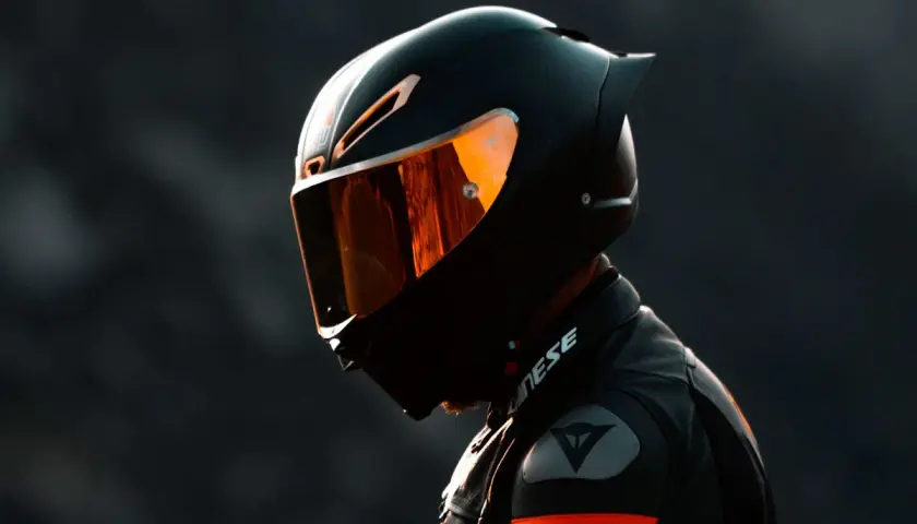 Motociclista con casco integral deportivo, uno de los tipos de cascos de moto, con visor naranja reflectante.