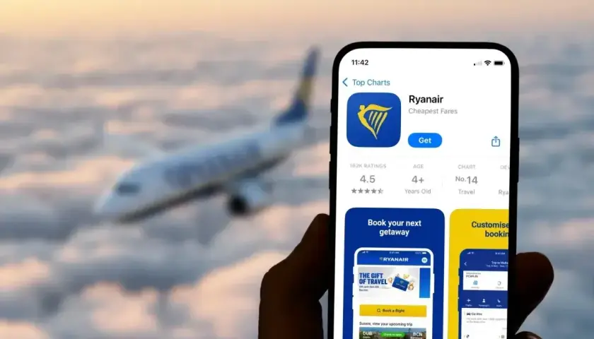 Telefon z aplikacją Ryanair, gotowy do rezerwacji lotu. W tle samolot przelatujący nad chmurami.