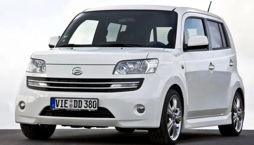 Biały Daihatsu Materia z niemieckimi tablicami rejestracyjnymi stoi na ciemnej nawierzchni.