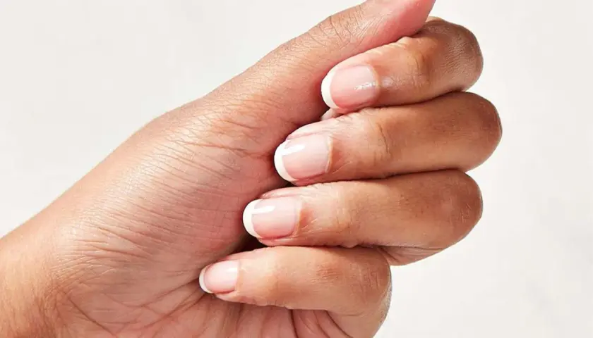 En hand med perfekt fransk manikyr och trind nagellack.