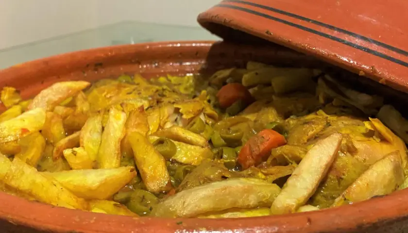 Un plat de tajine poulet olive, avec des pommes de terre dorées et des carottes, prêt à être dégusté.