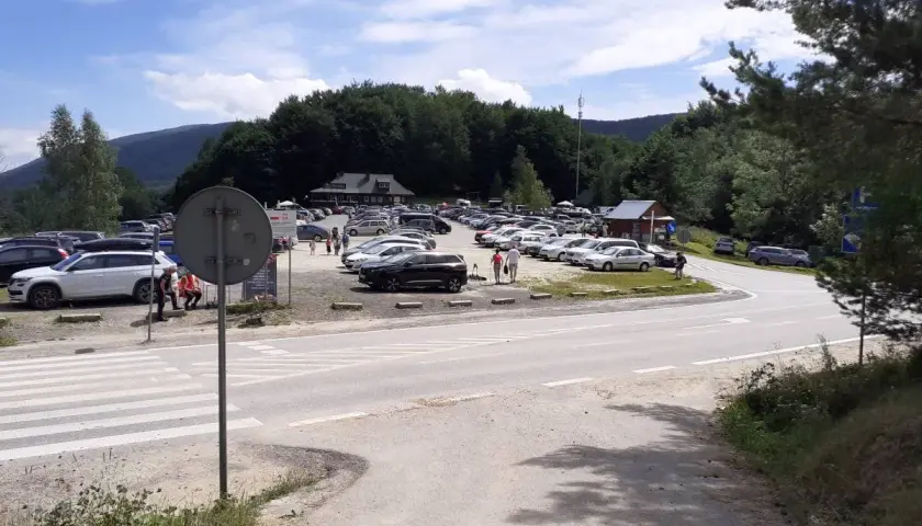 Duży parking na przełęczy wyżniańskiej, pełen samochodów podziwiających górskie krajobrazy.