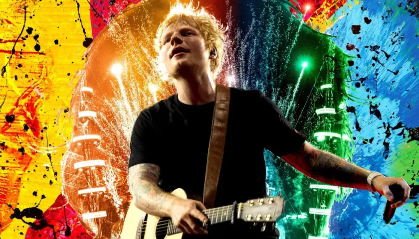 Ed Sheeran gra na gitarze na tle kolorowych eksplozji. Wyobraź sobie, kiedy Ed Sheeran zagra koncert w Polsce!