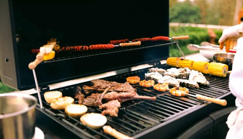 Viande, crevettes, huîtres et maïs sur un barbecue à gaz. Le fumage barbecue gaz ajoute une saveur délicieuse.