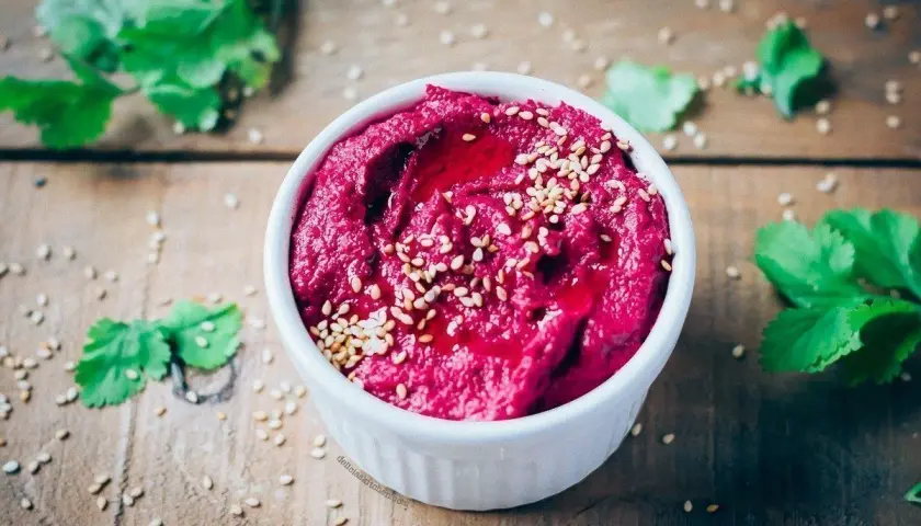Hummus de remolacha, una de las mejores remolacha recetas, adornado con semillas de sésamo y un chorrito de aceite.