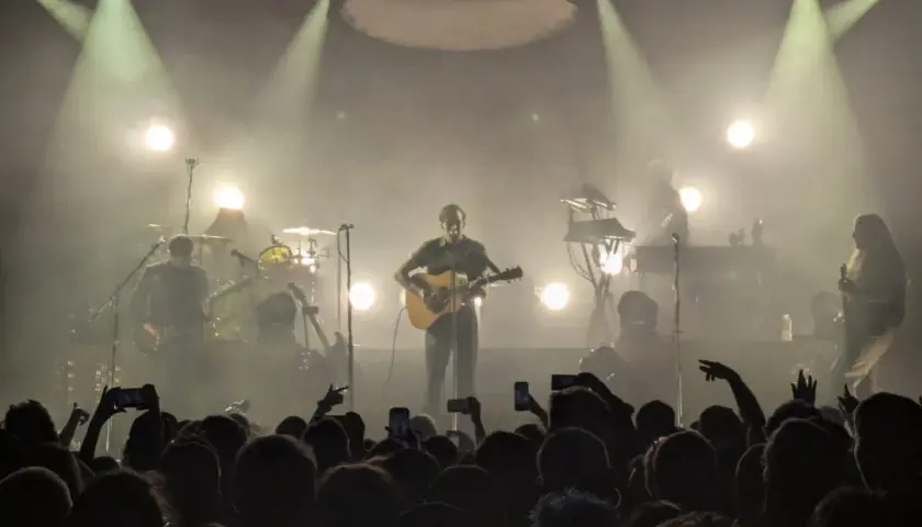 Koncertowy wokalista z gitarą, otoczony dymem i światłami. Publiczność wznosi telefony, wołając "nie zapomnij mnie".