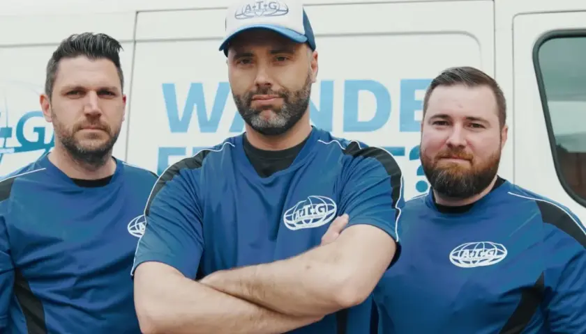 Drei Männer in blauen Arbeits-T-Shirts stehen vor einem weißen Transporter. Sie sind Teil des ATG-Teams, das sich auf Mauertrockenlegung spezialisiert hat.