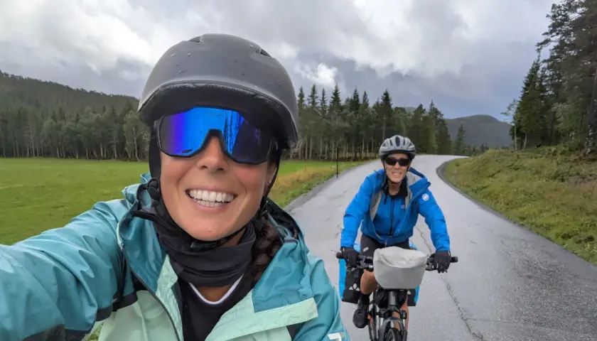 Dos ciclistas disfrutan de una ruta en bicicleta por un paisaje verde y montañoso, ¡una aventura EuroVelo España!