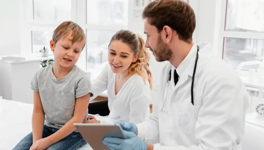 Medico di famiglia: gli orari, le nuove regole. Un dottore mostra un tablet a un bambino e sua madre, spiegando le novità.