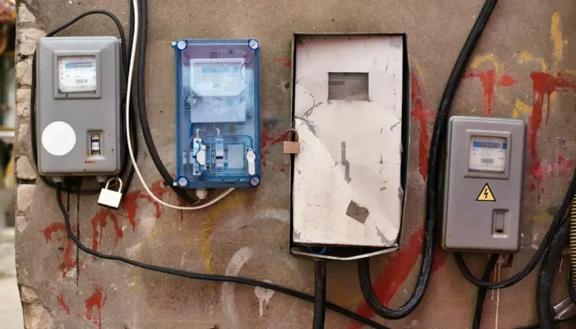 Cztery skrzynki z licznikami energii elektrycznej na ścianie. Jak włączyć bezpieczniki w domu? Sprawdź instrukcję przy skrzynce.