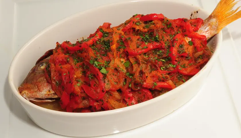 Pescado de roca gallego horneado con pimientos rojos y perejil.