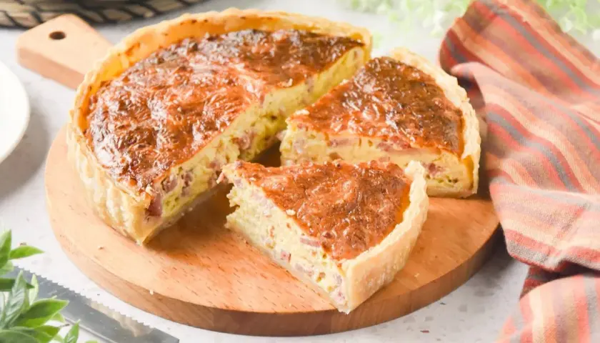 Un delicioso quiche de bacon, recién horneado y cortado en porciones, listo para disfrutar.