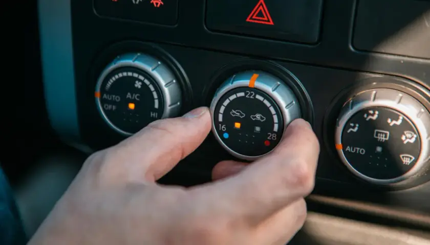 Dłoń kręci pokrętłem klimatyzacji. Zacięty termostat objawy mogą być widoczne jako brak reakcji na zmiany temperatury.